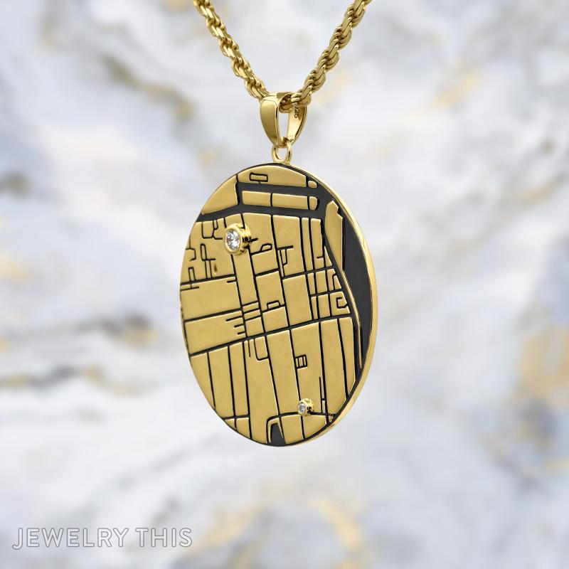 Round gold map pendant with engraved lines, black inlay, and two small round stones on a gold chain