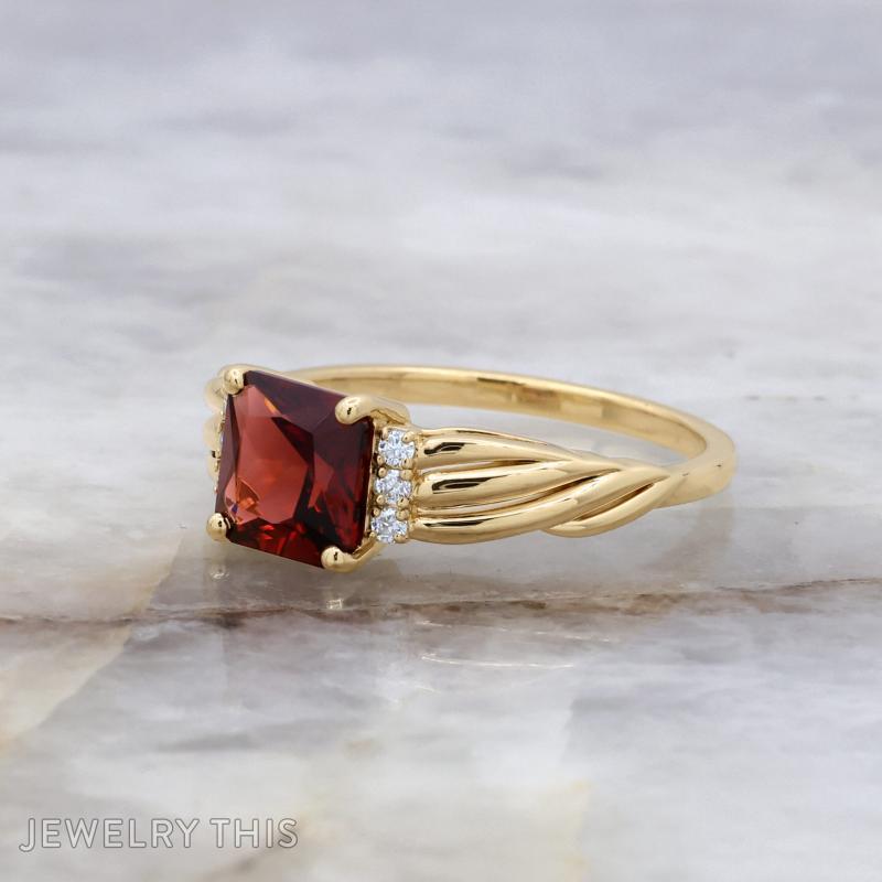 Custom engagement ring with radiant cut center stone, sculpted shoulders, and round accent stones.