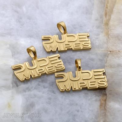 Gold cut-out logo pendant spelling DUDE WIPES with a polished bail.