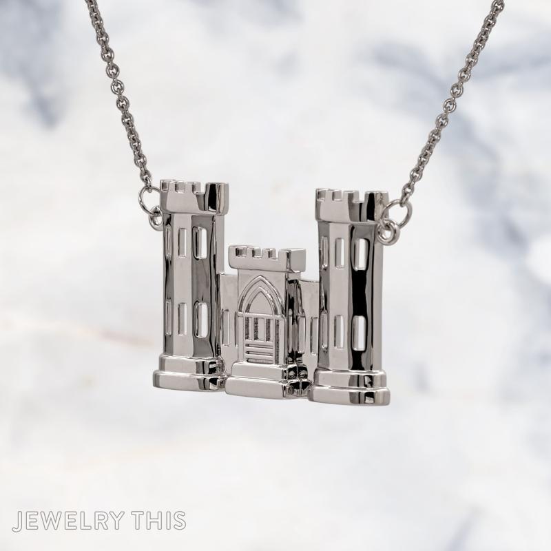 A sterling silver pendant shaped like a two-tower castle with a central gatehouse, featuring cut-out rectangular windows and crenellated tops, hanging from a silver cable chain against a marble background.