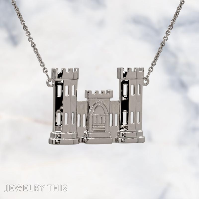 A sterling silver pendant shaped like a two-tower castle with a central gatehouse, featuring cut-out rectangular windows and crenellated tops, hanging from a silver cable chain against a marble background.